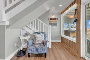 Living area featuring stairs, wood finished floors, wood walls, baseboards, and recessed lighting