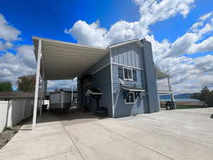 Back of house featuring driveway, board and batten siding, and an attached carport