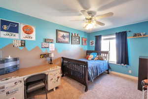 Bedroom with light colored carpet, baseboards, and a ceiling fan