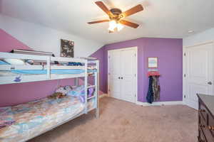 Bedroom with a closet, ceiling fan, baseboards, and light carpet