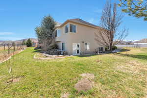 Back of property featuring stucco siding, fence, a mountain view, and a yard