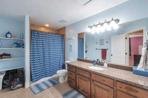 Full bath featuring a shower with curtain, tile patterned flooring, vanity, toilet, and visible vents
