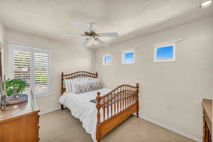 Bedroom with light colored carpet and a ceiling fan