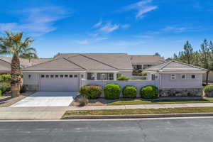 View of front of house featuring stone siding, a fenced front yard, an attached garage, stucco siding, and a tile roof