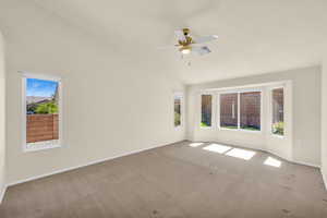 Carpeted spare room featuring plenty of natural light and a ceiling fan