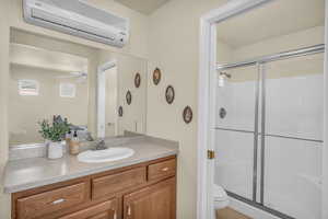 Full bathroom with a wall mounted air conditioner, a shower stall, vanity, and a ceiling fan