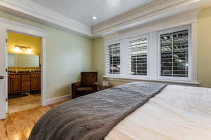 Bedroom featuring recessed lighting, light wood-type flooring, ornamental molding, baseboards, and connected bathroom