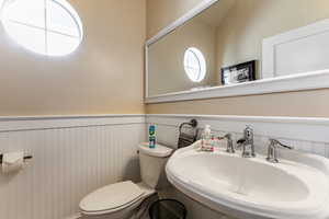 Bathroom with a sink, toilet, and wainscoting