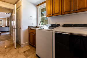 Washroom with a wealth of natural light, washer and clothes dryer, cabinet space, and a sink