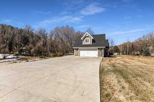 View of property exterior with driveway, a garage, a lawn, and fence