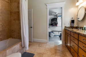 Bathroom with vanity, tiled shower / bath, and baseboards