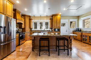 Kitchen featuring stainless steel appliances, a breakfast bar, a sink, a kitchen island, and brown cabinets