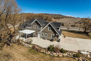Rear view of house featuring a lawn, a shingled roof, a mountain view, and a patio area