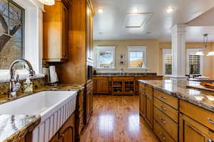 Kitchen with a sink, brown cabinets, light wood finished floors, and ornate columns