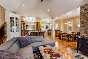 Living room featuring stairs, decorative columns, high vaulted ceiling, light wood-type flooring, and recessed lighting