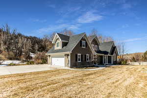 View of front facade featuring a front yard, concrete driveway, and roof with shingles