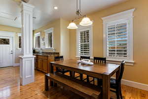 Dining space with baseboards, light wood-style flooring, recessed lighting, and decorative columns