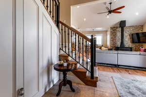 Stairway with vaulted ceiling, recessed lighting, a wood stove, a ceiling fan, and stone tile flooring