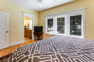 Bedroom with baseboards, recessed lighting, light wood-style floors, and ensuite bath