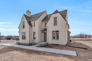View of front facade with fence, a chimney, stucco siding, a shingled roof, and a mountain view