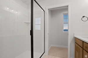 Full bathroom featuring a stall shower, baseboards, and vanity