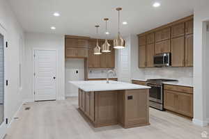 Kitchen featuring light countertops, recessed lighting, a sink, light wood-style floors, and appliances with stainless steel finishes
