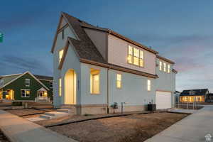 View of front facade featuring central air condition unit, driveway, a shingled roof, and an attached garage