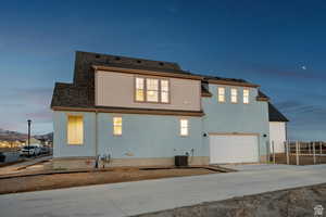 Back of property featuring driveway, an attached garage, central AC, and roof with shingles