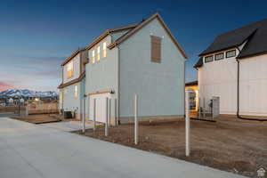 Rear view of house featuring central air condition unit, stucco siding, a garage, and concrete driveway, fencing to be installed soon.