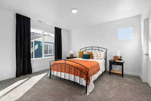 Carpeted bedroom featuring baseboards, multiple windows, and visible vents