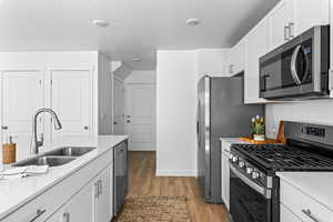 Kitchen with light countertops, a sink, stainless steel appliances, and dark wood finished floors