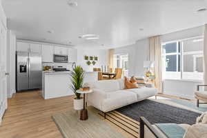 Living room with a textured ceiling, visible vents, and light wood finished floors