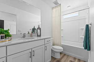 Bathroom featuring shower / bathing tub combination, vanity, toilet, visible vents, and wood finished floors