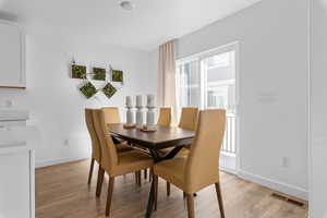 Dining space with baseboards, visible vents, and light wood-type flooring