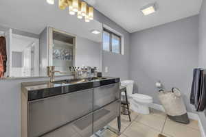 Bathroom featuring a shower, vanity, toilet, baseboards, and tile patterned floors
