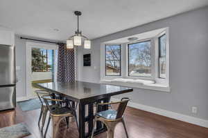 Dining room with dark wood-type flooring, baseboards, and a textured ceiling