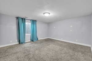 Carpeted empty room featuring baseboards, visible vents, and a textured ceiling