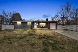 View of front of property with a gate, fence, an attached garage, concrete driveway, and a front lawn