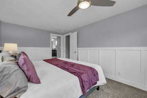Bedroom with wainscoting, carpet floors, and a ceiling fan