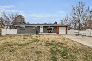 Ranch-style house with a front yard, a gate, fence, and an attached garage