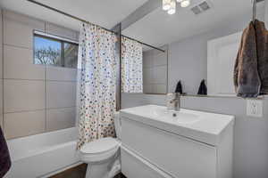 Bathroom with visible vents, toilet, shower / tub combo with curtain, and vanity