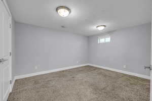 Basement featuring baseboards, a textured ceiling, visible vents, and carpet