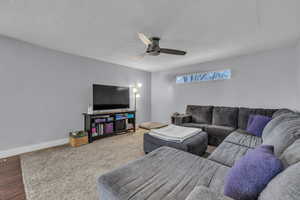 Living area featuring baseboards, a textured ceiling, ceiling fan, and wood finished floors