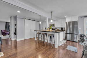 Kitchen featuring a kitchen breakfast bar, white cabinetry, dark countertops, a barn door, and appliances with stainless steel finishes