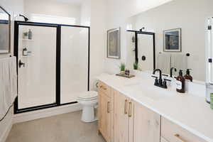 Full bathroom featuring a shower stall, tile patterned floors, toilet, and vanity