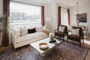 Living room with a notable chandelier, wood finished floors, and recessed lighting
