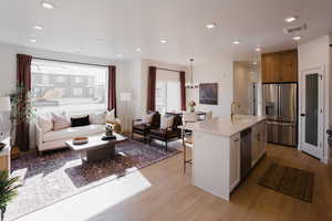Kitchen featuring a sink, open floor plan, light wood-style flooring, and appliances with stainless steel finishes