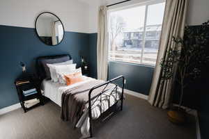 Carpeted bedroom with baseboards and multiple windows