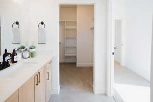 Bathroom with baseboards, tile patterned floors, a spacious closet, and vanity