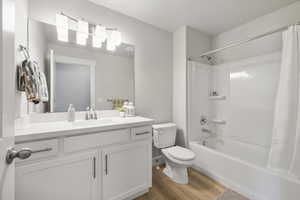 Full bathroom featuring shower / bathtub combination with curtain, wood finished floors, toilet, and vanity